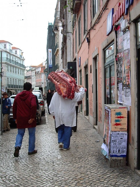 Meat A butcher casually carries a large portion of a cow to his butcher shop.
